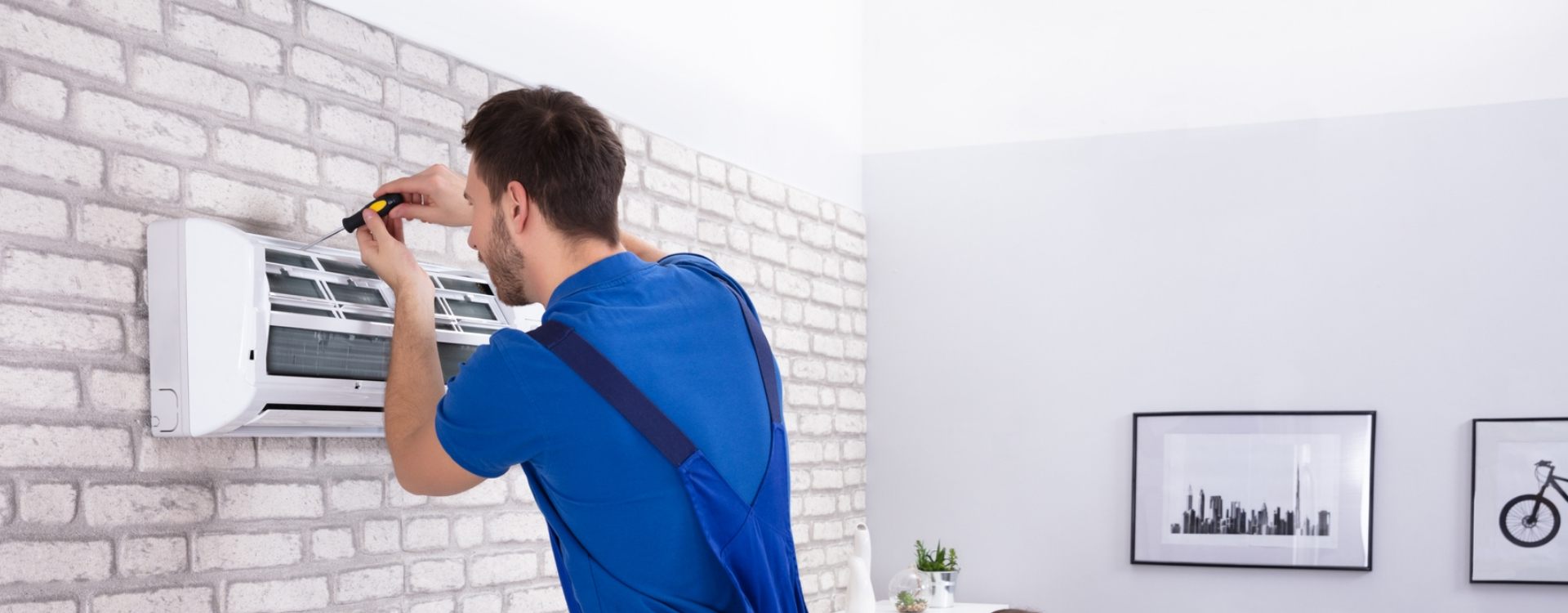 mężczyzna naprawiający klimatyzację na ścianie